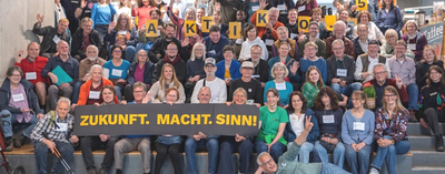 Ca. 80 Aktiko5-Teilnehmende im Gruppenfoto in mehreren Reihen auf einer Treppe sitzend